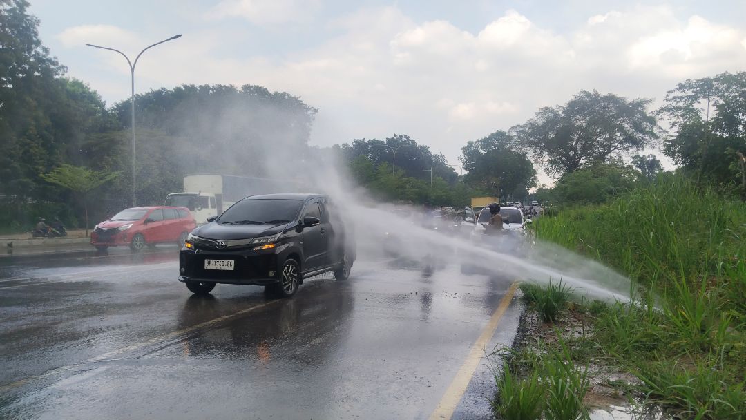 Semprotan air dari pipa bocor mengenai mobil yang melintas.