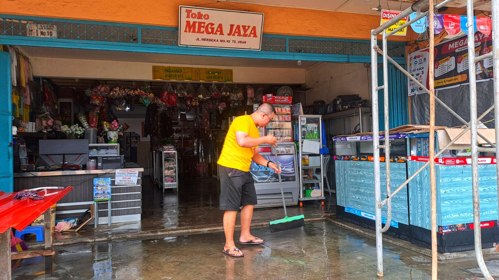 Warga membersihkan teras tokonya yang terdampak banjir rob di jalan Merdeka, Tanjunguban, Kecamatan Bintan Utara pada Minggu (7/12).