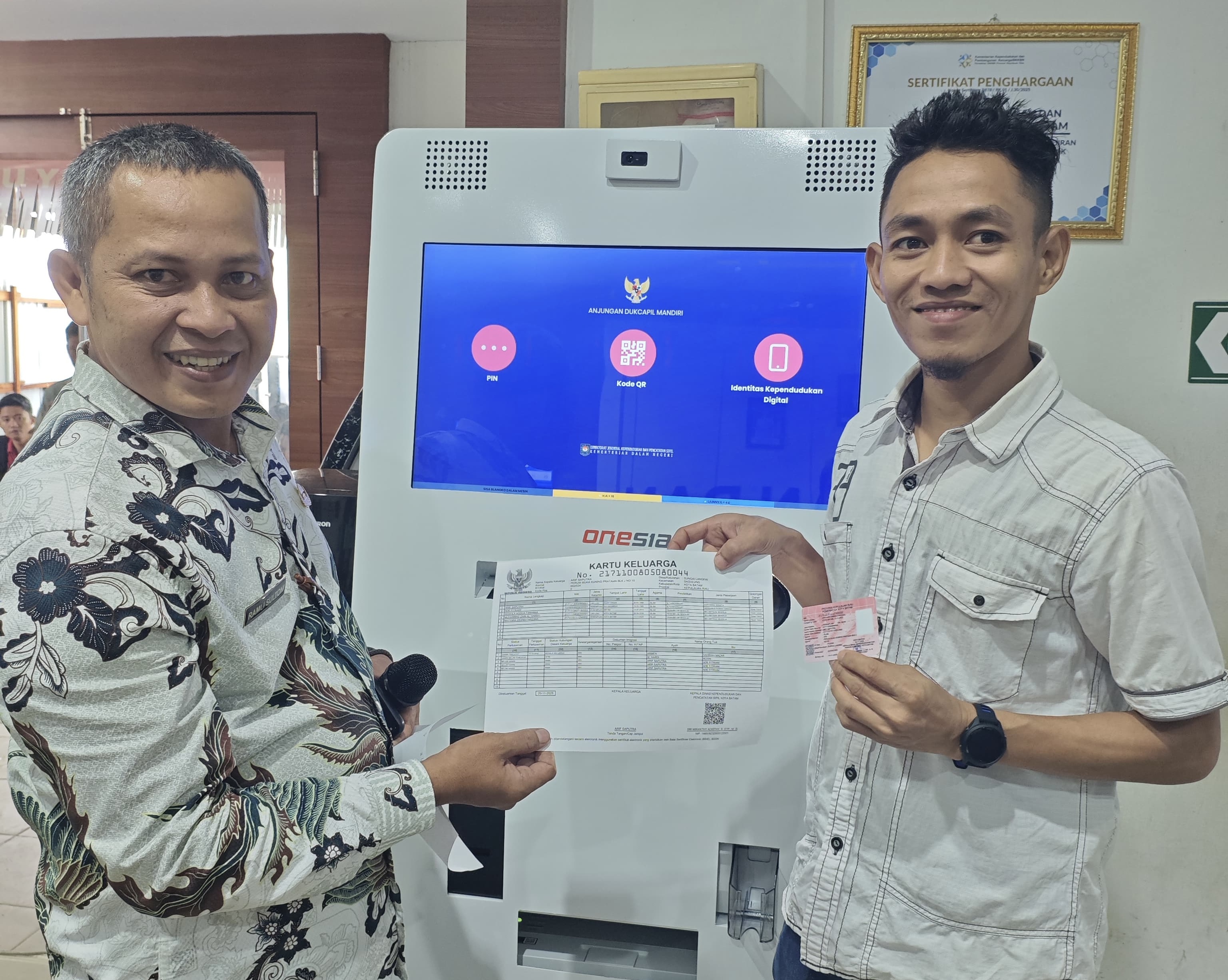 Seorang warga menerima KK yang dicetak secara mandiri di  Anjungan Dukcapil Mandiri (ADM).