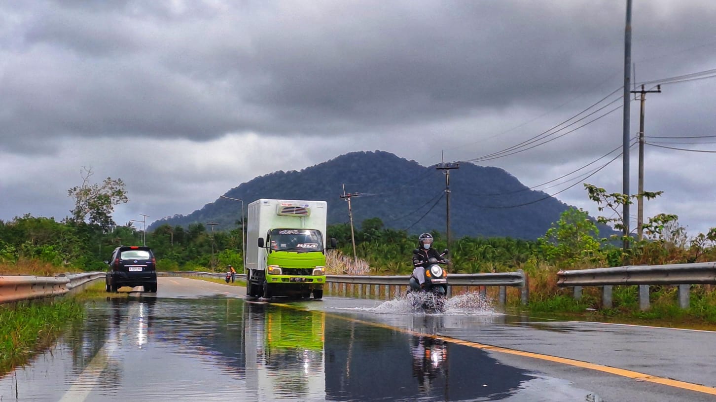 PENGENDARA motor menerobos banjir rob di jalan Lintas Barat, tepatnya di Desa Penaga, Kecamatan Teluk Bintan, Rabu (7/1/2026) siang. F.Slamet Nofasusanto/Batam Pos.