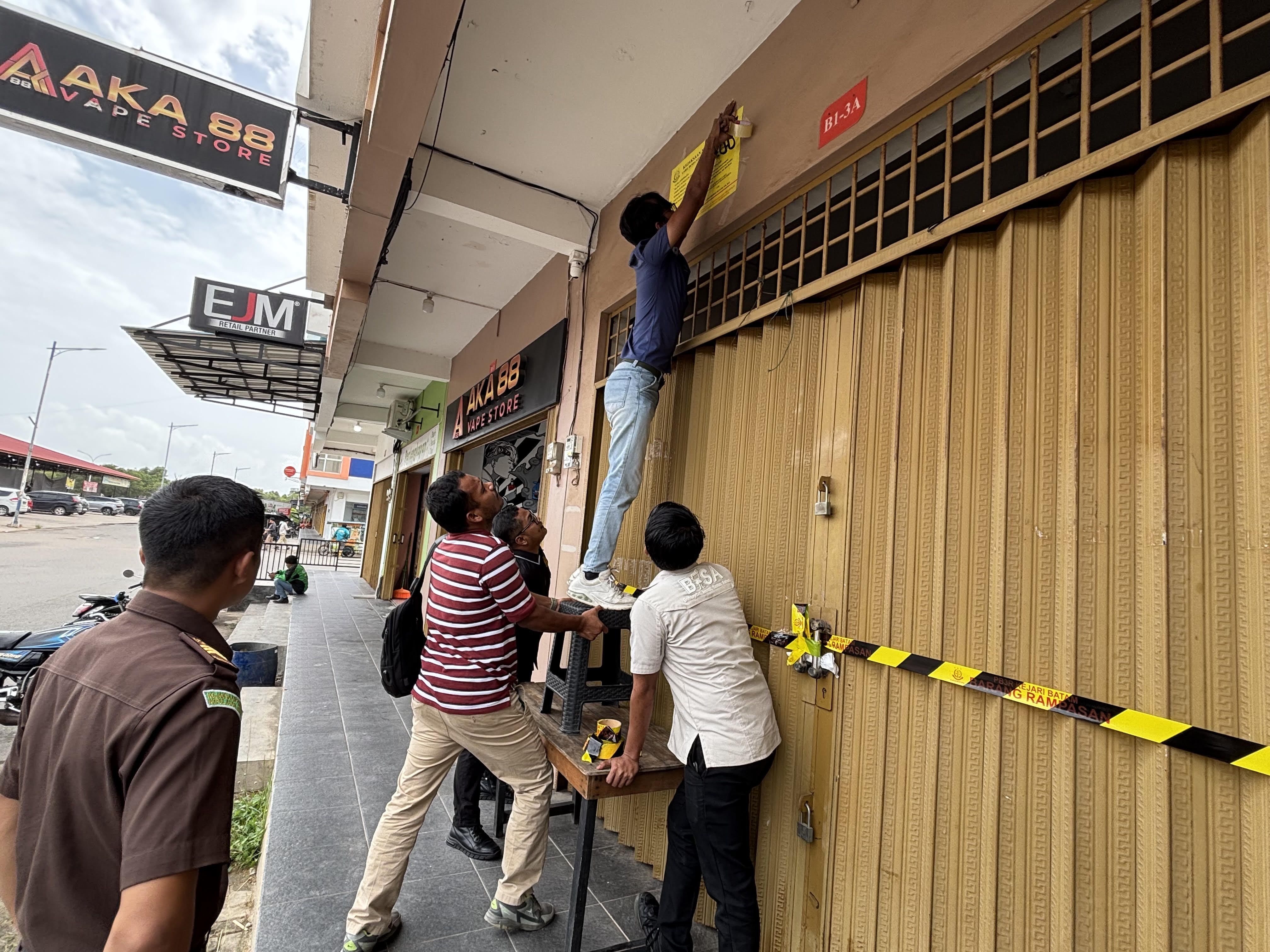 Petugas Kejari Batam memasang label dan segel barang rampasan negara di ruko Summerland Blok B1/03A, Kecamatan Nongsa, Batam, Kamis (8/1/2026). F. Yashinta/Batam Pos