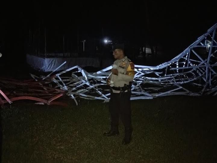 PETUGAS satpam berdiri di depan menara telekomunikasi Telkomsel yang ambruk di Desa Kelarik, Kecamatan Bunguran Utara, Kabupaten Natuna, Kamis, (8/1/2026) sekitar pukul 22.00 WIB.