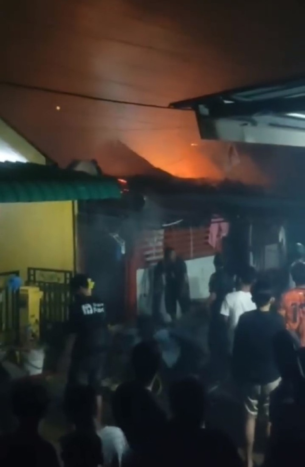 Warga berupaya memadamkan api dengan alat seadanya yang melalap dua rumah di Perumahan Permata Asri 1 Tahap 1, Kecamatan Sei Beduk, ludes terbakar, Sabtu (24/1) malam. F. tangkapan layar video grup WA