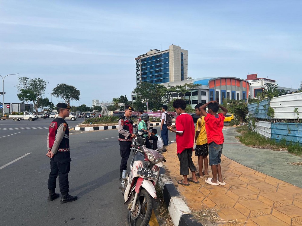 Tiga pelajar yang masih duduk di bangku SMP ditegur polisi karena mengendarai sepede motor berboncengan tiga tanpa helm. F. M. Sya