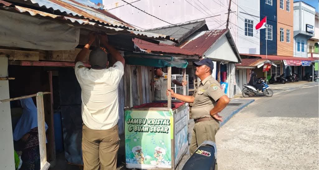 PETUGAS Satpol PP Lingga saat menertibkan grobak dagangan yang masih berjualan di atas trotoar, Rabu (28/1/2026). F. Hasim untuk BATAM POS