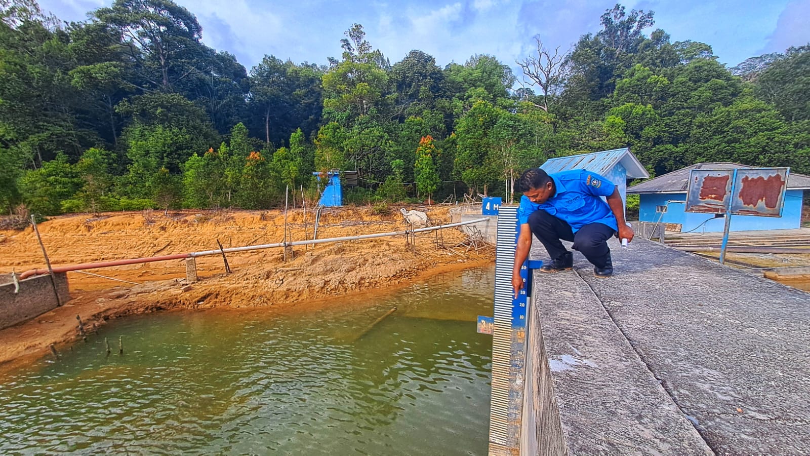 PETUGAS Waduk Sei Jago menunjukkan ketinggian air di waduk yang terletak di Desa Lancang Kuning, Kecamatan Bintan Utara. F.Slamet Nofasusanto/Batam Pos.