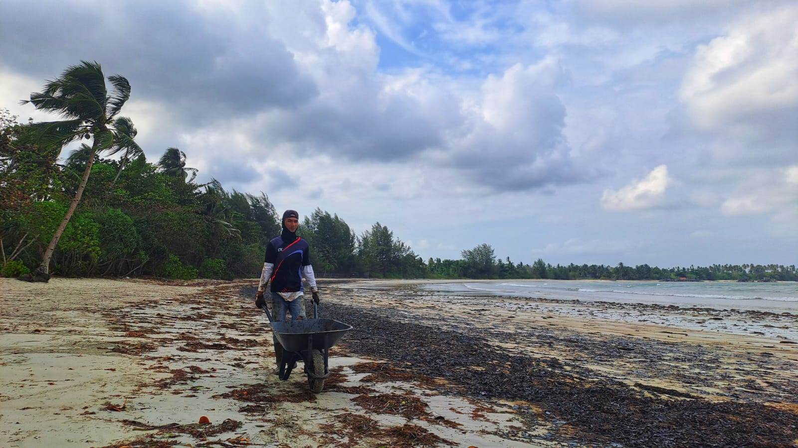PETUGAS Pantai di Jalan Trikora Kabupaten Bintan tampak mendorong gerobak berisikan limbah minyak yang mengotori pantai Mutiara Beach Resort. F. F. Slamet Novasusanto/Batam Pos