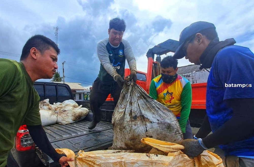 Pegawai DLHK Kepri memindahkan karung baru berisi limbah minyak hitam ke dalam jumbo bag sebelum diangkut truk transporter di Pantai Trikora, Bintan, Rabu (11/2). F. Slamet Nofasusanto/Batam Pos.
