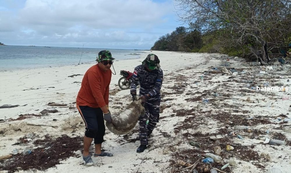 Warga bergotong-royong membersihkan karung berisi limbah minyak hitam yang terdampar di Pantai Belakang, Desa Mapur, Kecamatan Bintan Pesisir, Senin (16/2).