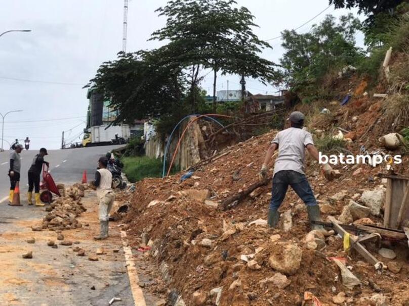  Petugas Dinas Bina Marga Kota Batam melakukan perbaikan dan penataan ulang material sisa longsor yang menutup sebagian badan Jalan Bengkong Baru, Jumat (20/2) siang. F. M. Sya&rsquo;ban / Batam Pos