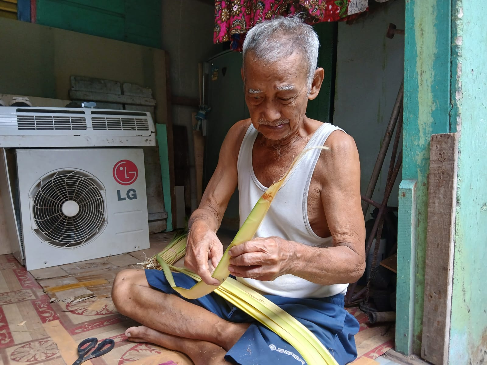 Sabran (82) sedang membersihkan daun kelapa sebelum dimulai tahap menganyam ketupat. F Ihsan Imaduddin/Batam Pos