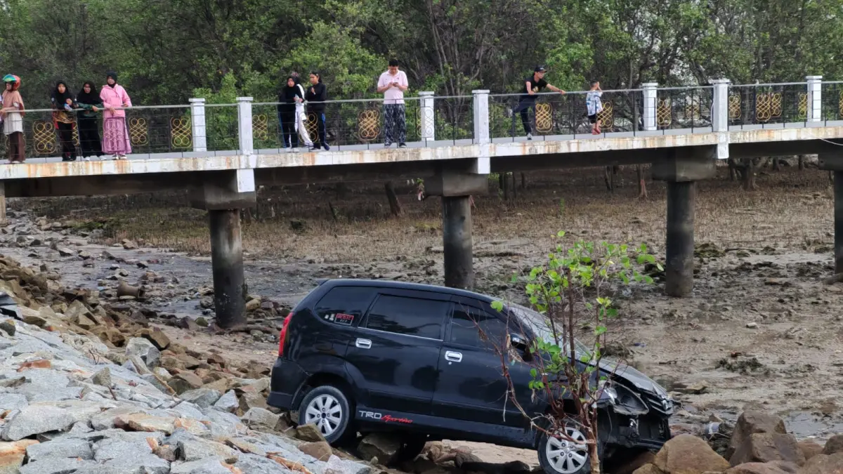 MOBIL Avanza ke luar jalur dan masuk sampai ke atas batu pemecah ombak usai menabrak beberapa pengendara sepeda motor di Coastal Area, Tanjungbalai Karimun, Minggu (19/4/2026). F Sandi Pramosinto/Batam Pos.
