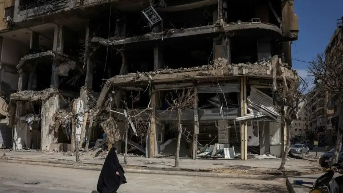 Seorang wanita berjalan melewati bangunan yang rusak di tengah gencatan senjata 10 hari antara Lebanon dan Israel, di Beirut, Lebanon. (Marko Djurica/Reuters).
