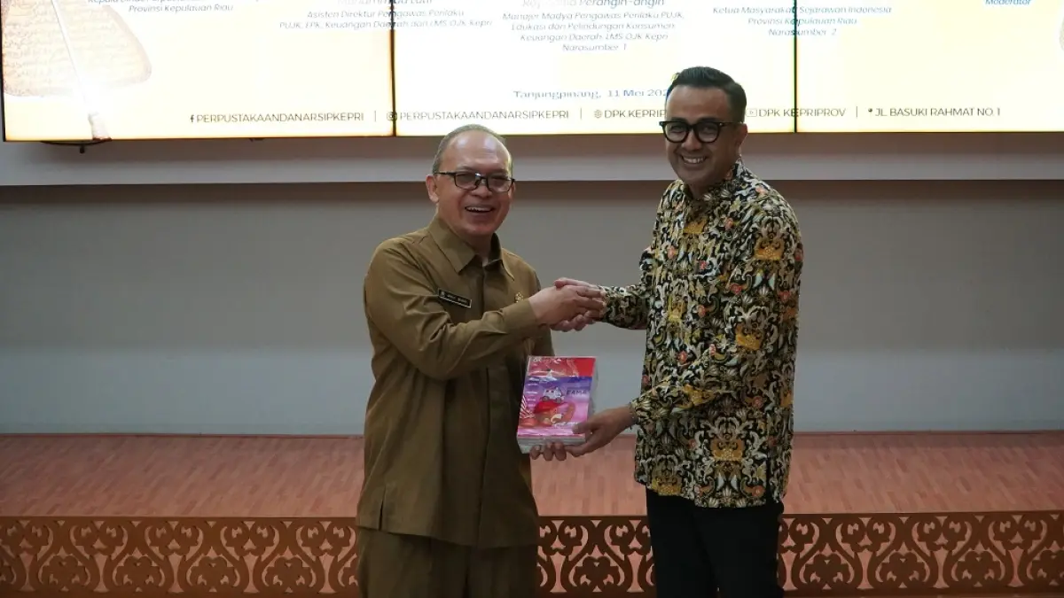 Asisten Direktur Bagian Pelindungan Konsumen OJK Kepulauan Riau, mewakili Kepala OJK Kepri Muhammad Lutfi (kanan), menyerahkan buku kepada Kepala Dinas Perpustakaan dan Kearsipan Provinsi Kepri, Moh. Bisri, di sela seminar Konsep Keuangan dalam Pemikiran Raja Ali Haji yang digelar OJK Kepulauan Riau bersama Dinas Perpustakaan dan Kearsipan Provinsi Kepri di Tanjungpinang, Jumat (15/5). Foto: Istimewa 
