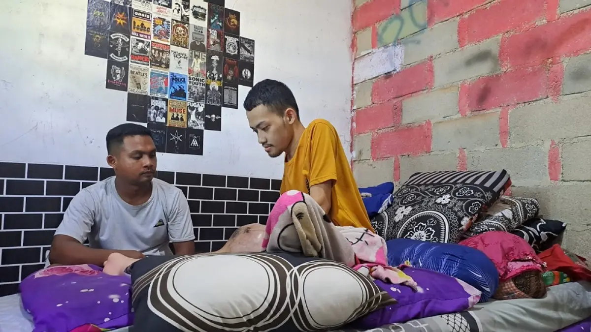 Iswandi, penderita kanker tulang ditemani abangnya, Roni saat berada di tempat tidurnya, di rumahnya, Kampung Sialang, Desa Berakit, Kecamatan Teluk Sebong. F. Slamet Nofasusanto/Batam Pos