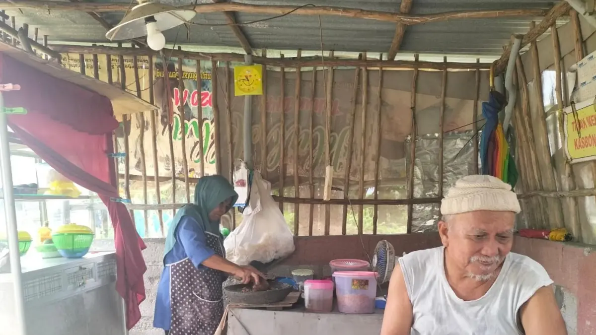 Sakti Indrawan menemani istrinya Endang Sriwahyuni berjualan lontong pecel di RT 004 RW 009 Kampung Jeruk, Tanjunguban, Selasa (9/6/2026) siang. F.Slamet Nofasusanto/Batam Pos