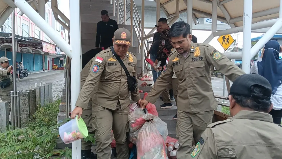 Petugas Satpol PP Karimun mengamankan barang-barang Wt, perempuan dengan dugaan kesehatan mental dari JPO, Kamis (11/6/2026). F Sandi Pramosinto/Batam Pos