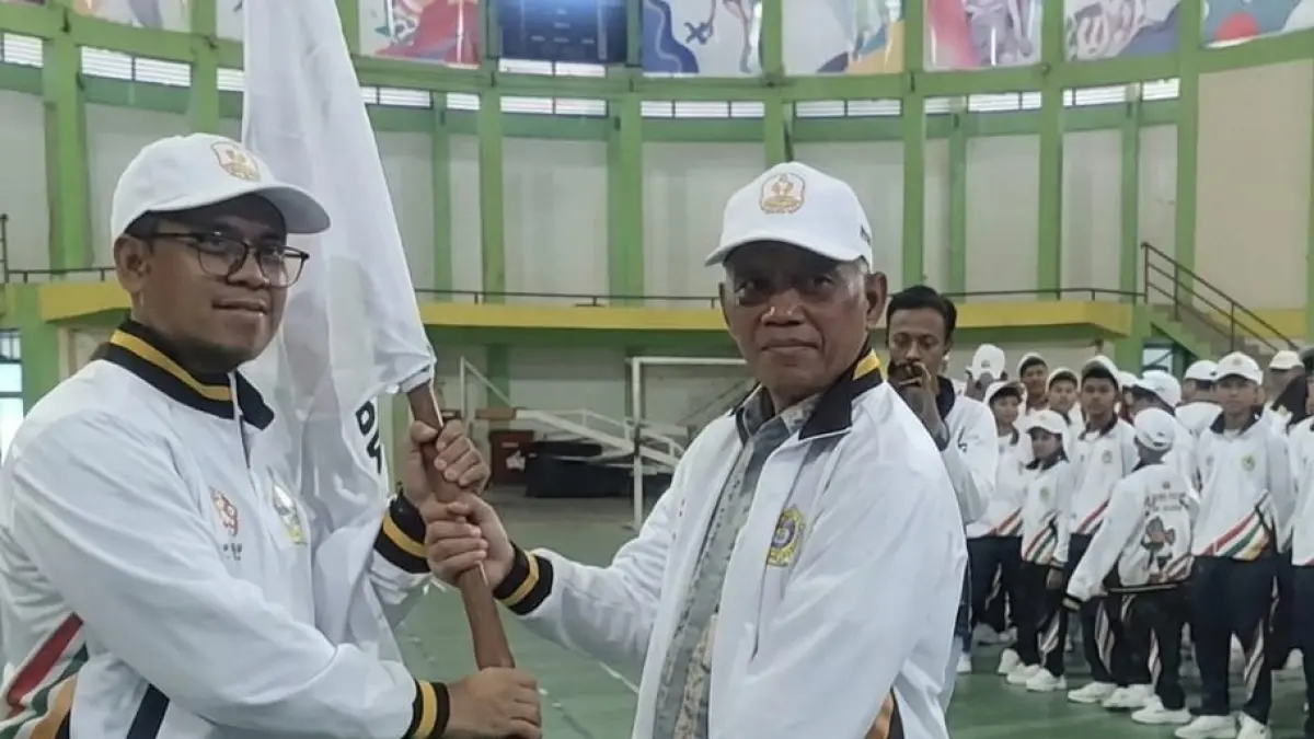 Bupati Karimun, Iskandarsyah (kiri), menyerahkan bendera kontingen Popda X 2026 Kabupaten Karimun kepada Sularno selaku Ketua Kontingen Kabupaten Karimun. F Sandi Pramosinto/Batam Pos