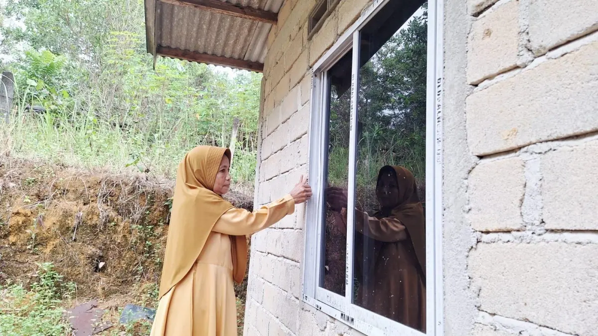Kastini menunjukkan jendela bagian belakang yang rusak akibat dicongkel. F.Romy untuk Batam Pos