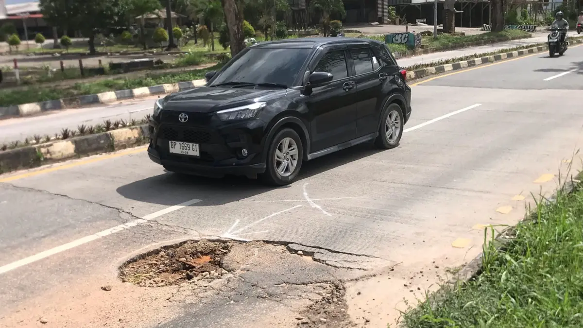 Pengendara mengurangi kecepatan dan menghindari lubang menganga di Jalan Engku Putri, depan kawasan Ikan Daun, Batam Centre, Senin (6/7). Foto: M. Sya