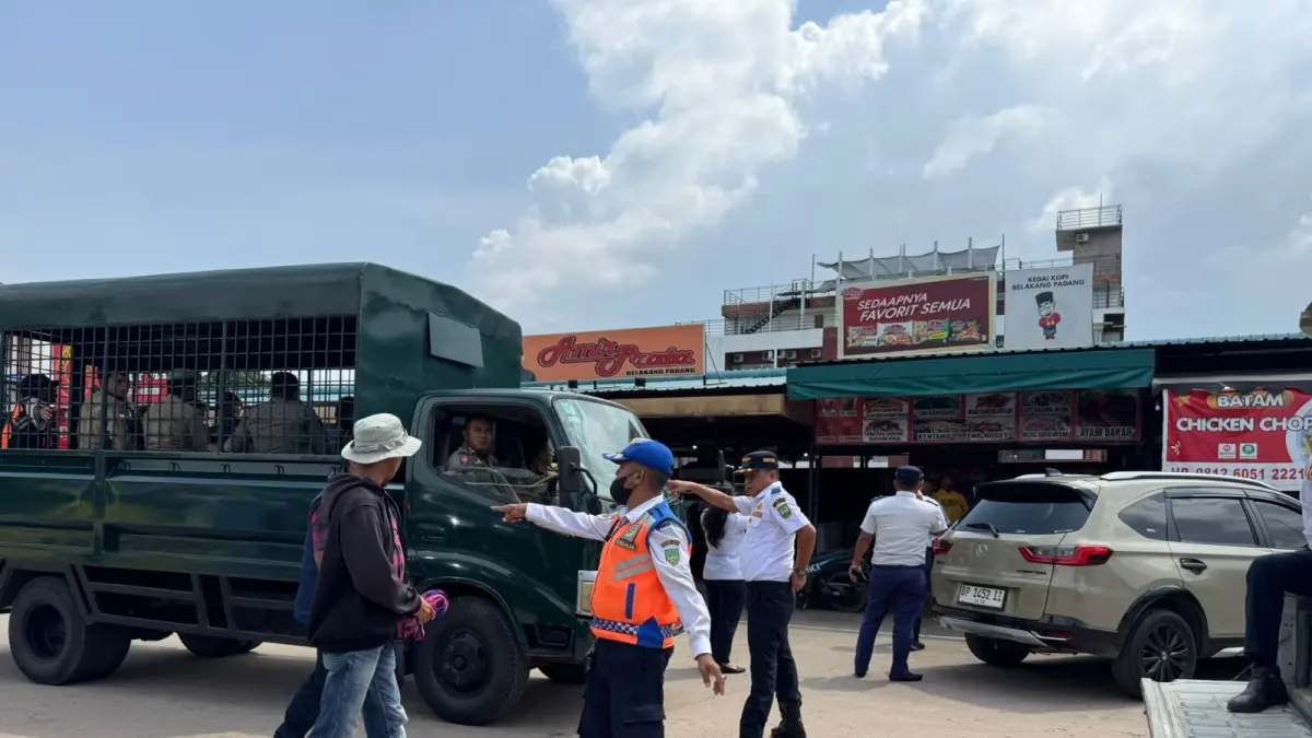 Petugas Dinas Perhubungan Kota Batam mengamankan seorang juru parkir liar saat operasi penertiban di kawasan Sekupang dan Nagoya, Senin (13/7). Dalam razia tersebut, enam juru parkir tanpa izin terjaring setelah kedapatan tetap memungut uang parkir di lokasi yang izin pengelolaannya telah dicabut. Foto: M. Sya