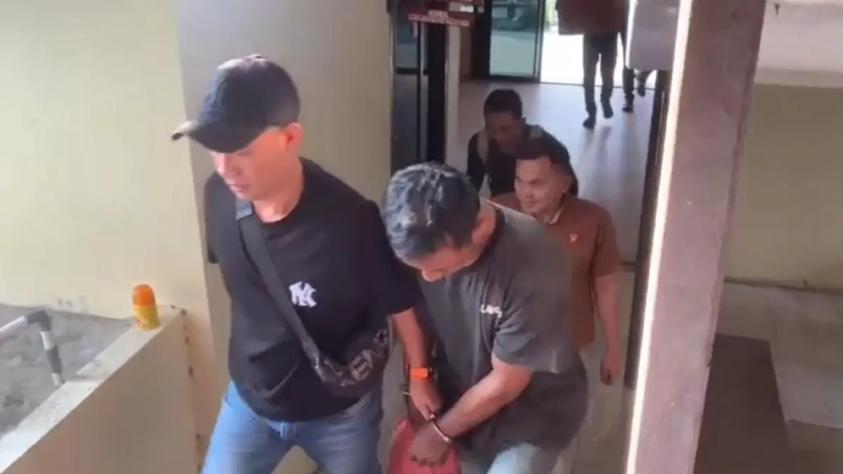 Pelaku AD saat digiring masuk ke ruang pemeriksaan Mapolsek Bukit Bestari Tanjungpinang, Selasa (22/7). F. Mohamad Ismail/Batam Pos

