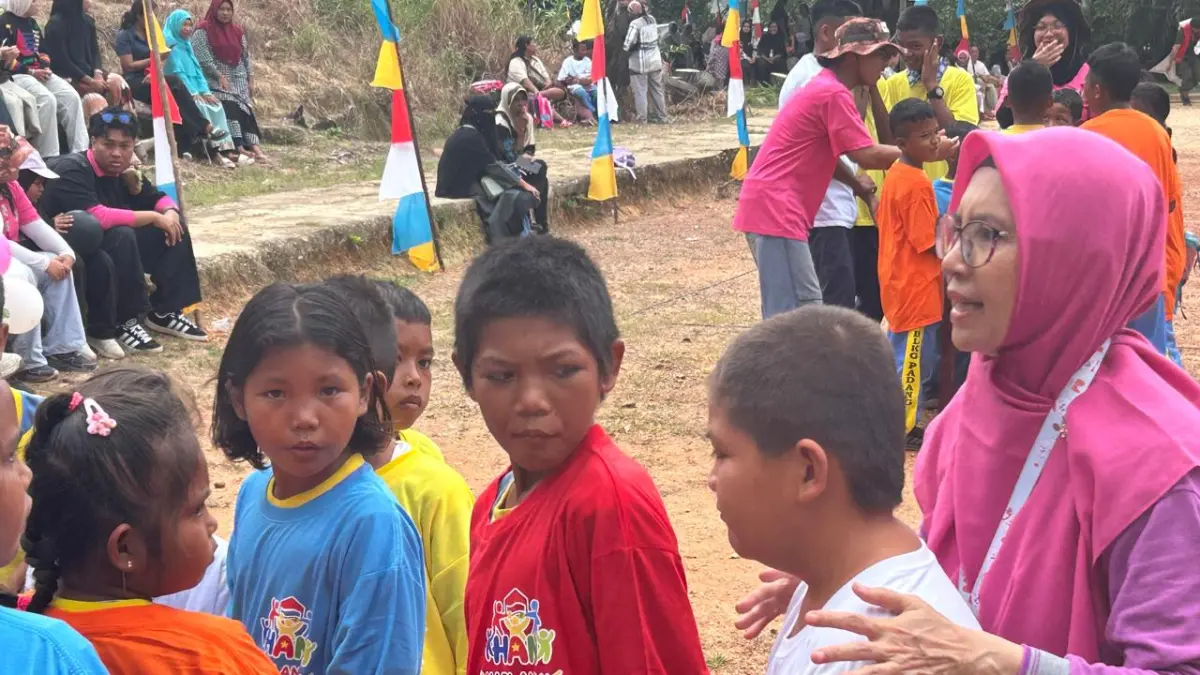 Panitia HAN 2026 dari KKKS Batam, Setyasih Priherlina mengarahkan Aleando alias Bule,9, korban perundungan yang putus sekolah untuk turut bermain bersama kelompok anak. F Chahaya Simanjuntak/Batam Pos