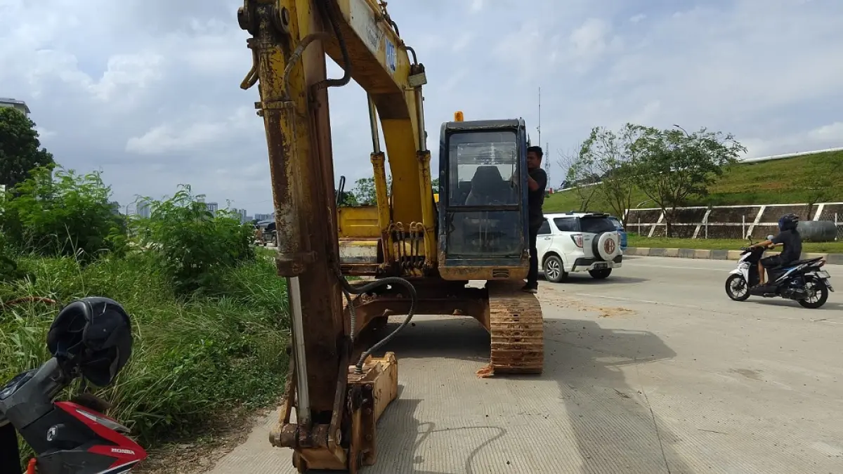 Satu unit alat berat mulai disiagakan di lokasi pada Jumat (24/7) sore. Pekerja tampak mempersiapkan pembongkaran badan jalan yang selama ini mengalami penurunan permukaan hingga membentuk gelombang. Foto: M. Sya