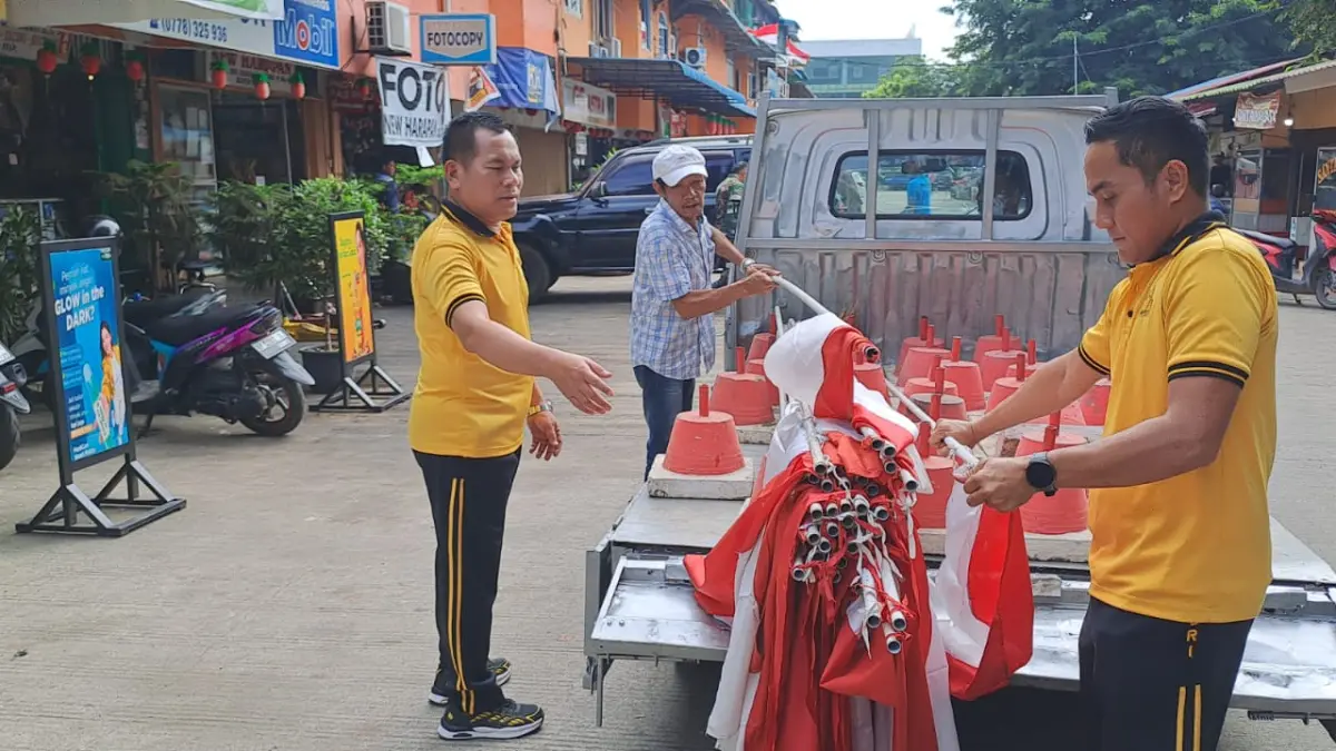 Warga dan aparat gotong royong memasang bendera Merah Putih di sepanjang kawasan pasar Seiharapan, Jumat (31/7).