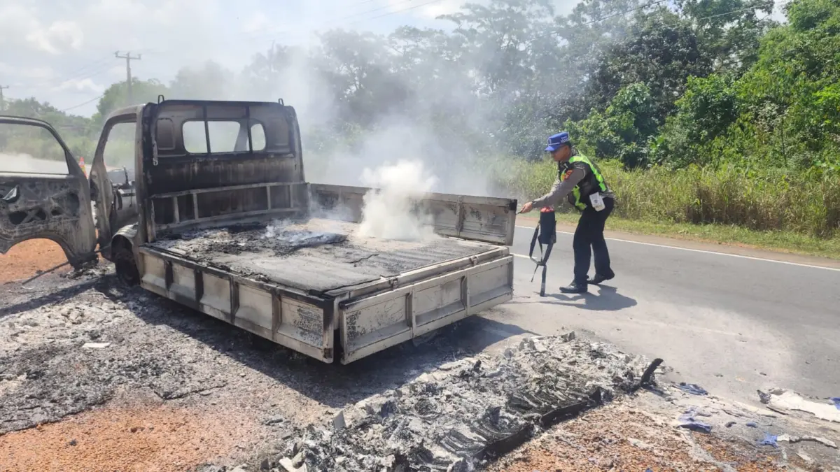 Petugas Polres Bintan memadamkan api yang membakar pikap di Jalan Raya Wan Seri Beni, tepatnya di jalur sebelah kanan dari arah Kantor Bupati Bintan, Desa Bintan Buyu, Kecamatan Teluk Bintan, Sabtu (1/8). Foto: H.P. Bako untuk Batam Pos