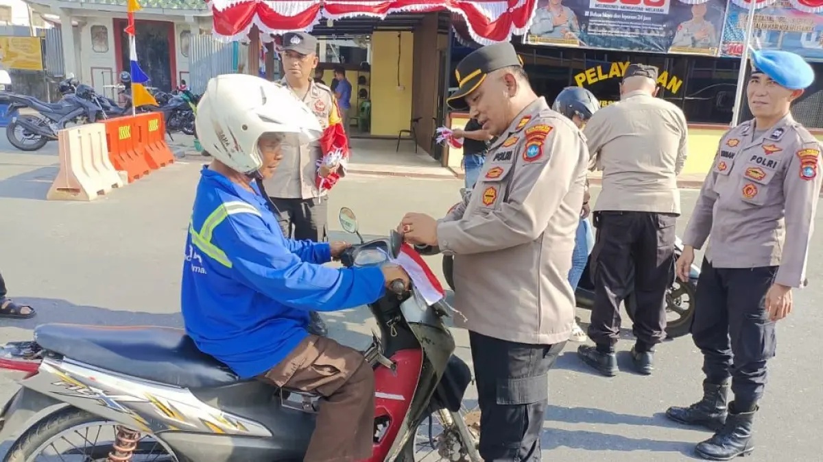 Polsek Tanjungpinang Kota membagikan ratusan bendera merah putih ke pengendara yang melintas di Jalan Merdeka. Foto: Mohamad Ismail/Batam Pos

