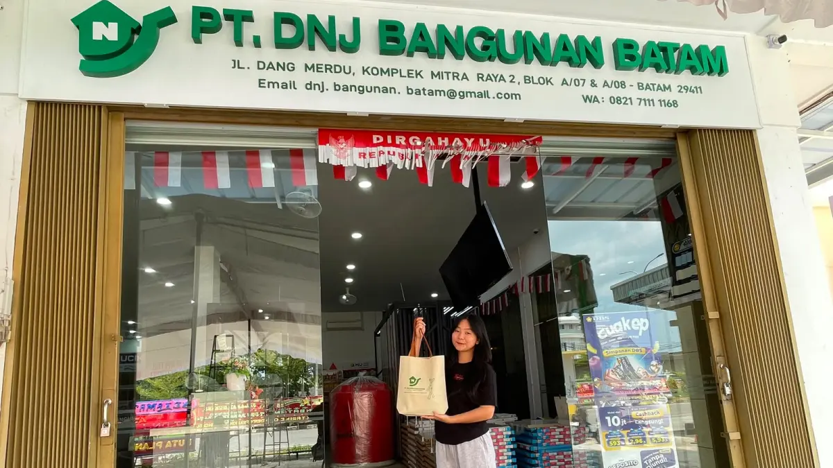 Salah seorang pegawai PT DNJ Bangunan Batam menenteng tas belanja di depan toko, Minggu (9/8), sehari sebelum grand opening. Foto: M. Sya’ban/ Batam Pos