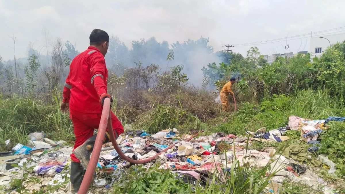 Petugas memadamkan api yang membakae lahan di depan Perumahan Permata Laguna Marina, Senin (10/8). F.Rengga Yuliandra/Batam Pos
