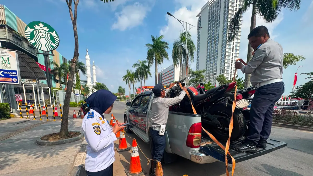 Petugas Dinas Perhubungan (Dishub) Kota Batam menaikkan sepeda motor yang terjaring penertiban parkir liar ke atas mobil derek di kawasan depan Pelabuhan Internasional Batam Center, Selasa (11/8). F. M. Sya’ban / Batam Pos