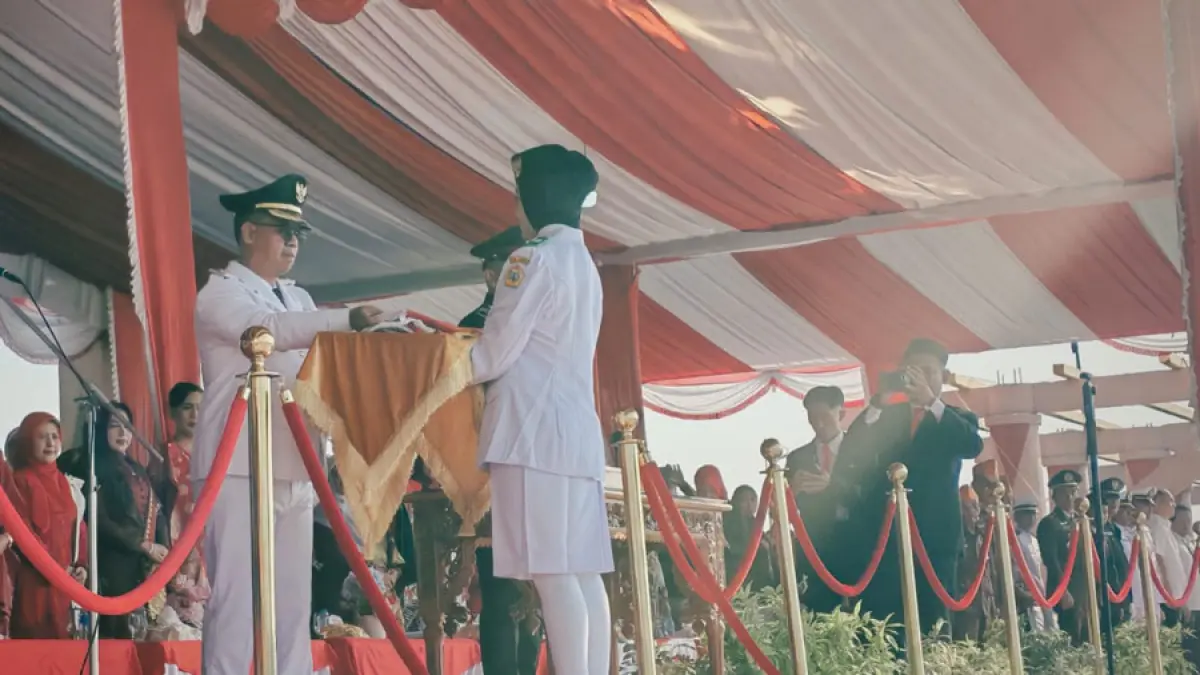 Bupati Karimun, Iskandarsyah menyerahkan bendera kepada pembawa bendera merah putih pada upacara bendera HUT ke-81 Republik Indonesia di Panggung Rakyat Puteri Kemuning.  F. Sandi Pram / Batam Pos