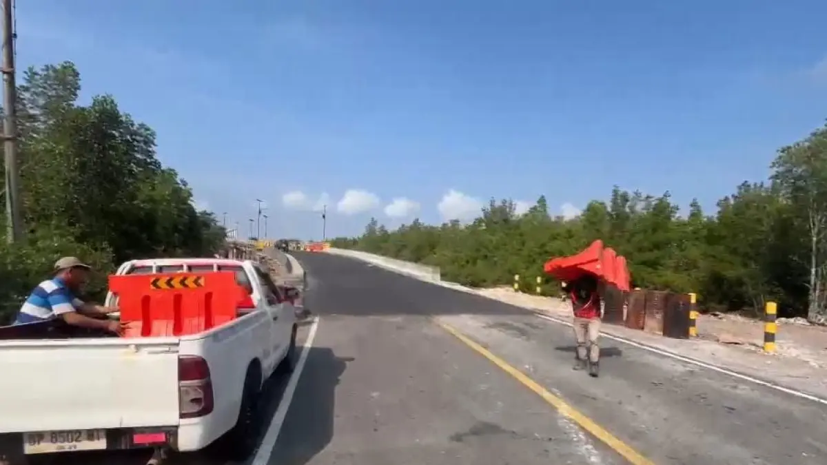 Petugas membuka dan memindahkan pembatas jalan yang sebelumnya menutup akses jalan di lokasi jembatan yang diperbaiki di jalan Lintas Barat, Bintan. F.Kiriman Mulyadi untuk Batam Pos.