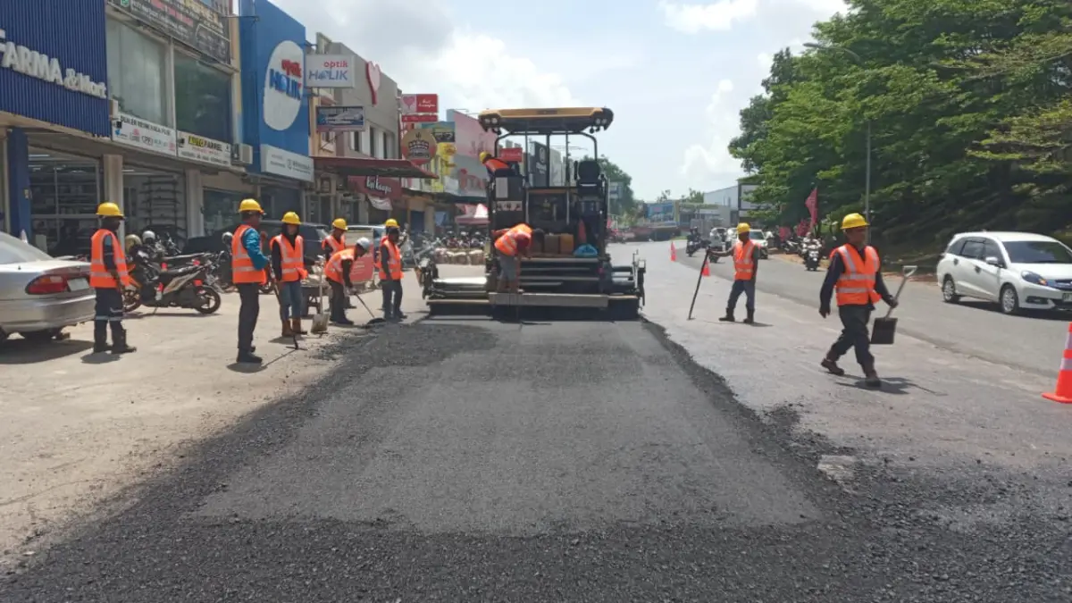 Pekerja bersama satu unit alat berat melakukan perbaikan Jalan Industri Tunas 2 di kawasan Botania 2, Batam.