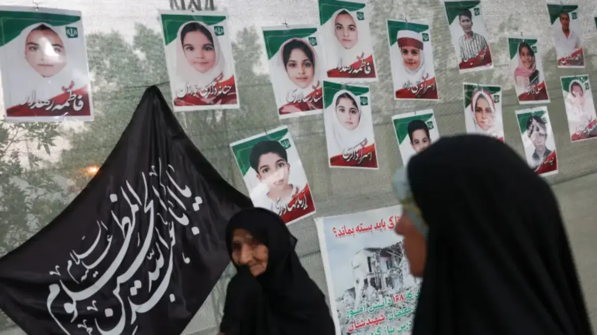 Para perempuan berada di depan gambar yang menampilkan murid-murid sekolah dasar Minab yang tewas dalam serangan udara AS pada 28 Februari, di Minab, Iran. (Majid Asgaripour/WANA/Reuters)