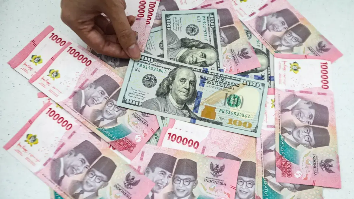Teller menunjukan mata uang Dolar AS dan Rupiah. (Jawa Pos)