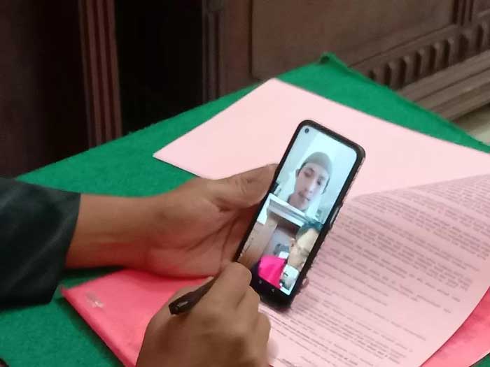 Aries disidang secara daring di PN Surabaya. Kasus pengeroyokan. (MAHRUS/RADAR SURABAYA)