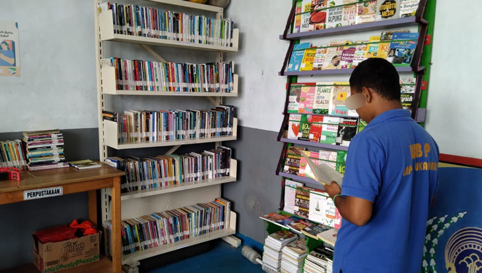 PERPUSTAKAAN: Salah seorang warga binaan sedang memilih dan membaca buku di perpustakaan mini Lapas Sukamara.