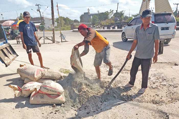 GOTONG ROYONG: Warga menambal Jalan GM Arsyad dan di seputaran Bundaran Tudung Saji, Kelurahan Baru, Minggu (15/9).  &nbsp;