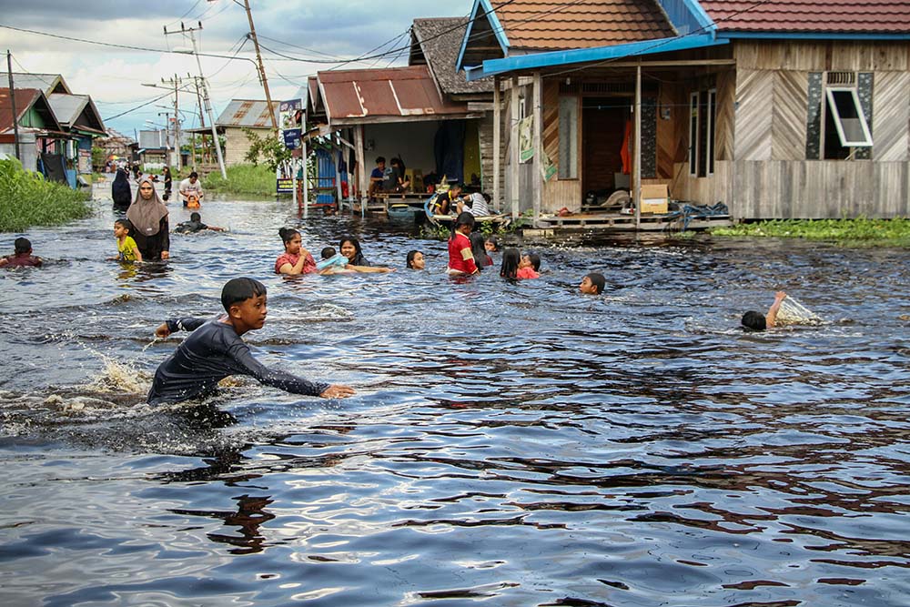 Warga bermain air di kawasan permukiman Jalan Anoi, Palangka Raya, Kalimantan Tengah, Sabtu (30/11/2024). Banjir akibat luapan Sungai Kahayan tesebut merendam kawasan Jalan Anoi dan permukiman warga dengan ketinggian air hingga 70 sentimeter. ANTARA FOTO/
