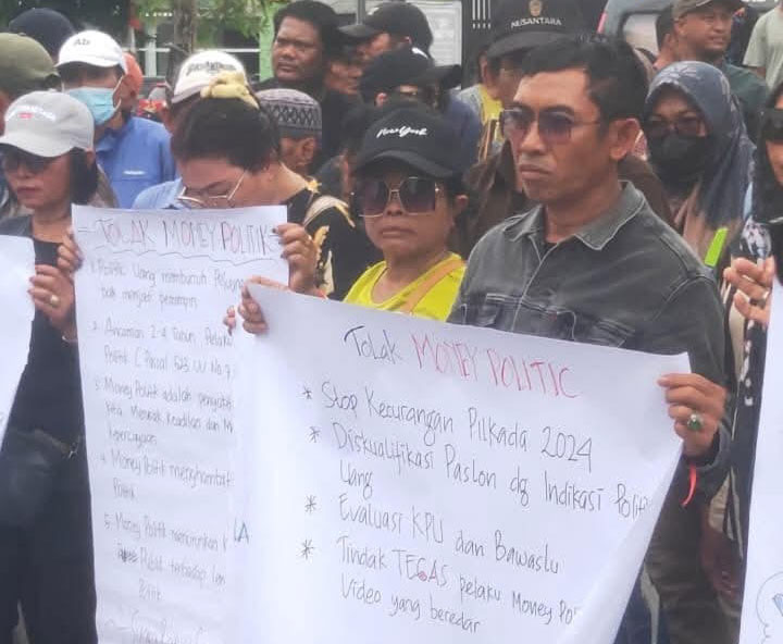 TOLAK POLITIK UANG: Peserta aksi protes membentangkan poster di depan Kantor KPU Kapuas, Kuala Kapuas, Selasa (10/12)