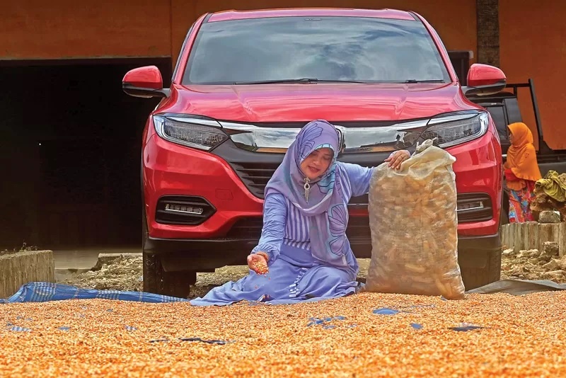 TETAP BERTANI: Siti Nurul Hidayatin, warga Sumurgeneng, memasukkan jagung ke dalam glangsing. Mayoritas warga Sumurgeneng bertani dan beternak. &nbsp;RIANA SETIAWAN/JAWA POS