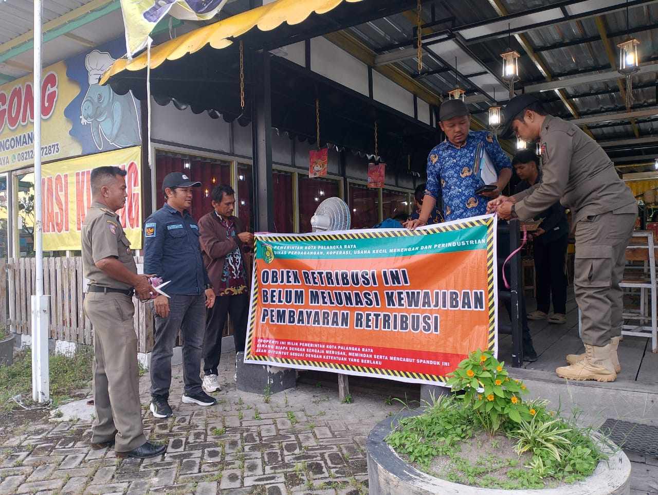 Tim gabungan, Satpol PP dan DPKUKMP Kota Palangka Raya, melakukan pemasangan spanduk peringatan retribusi daerah di kawasan kuliner Tunggal Sangumang Yos Sudarso.