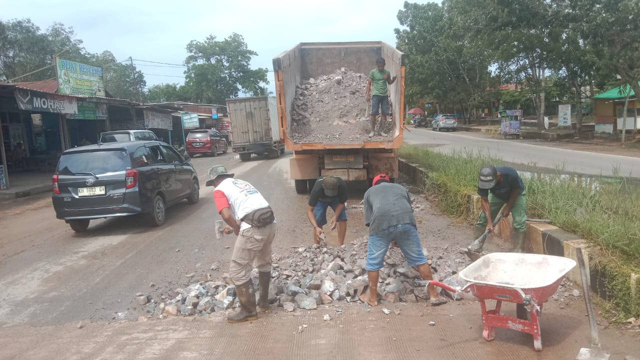 GOTONG ROYONG: Warga bergotong royong menimbun lubang Jalan Poros Utama Desa Karang Mulya, Kecamatan Pangkalan Banteng. (Istimewa)