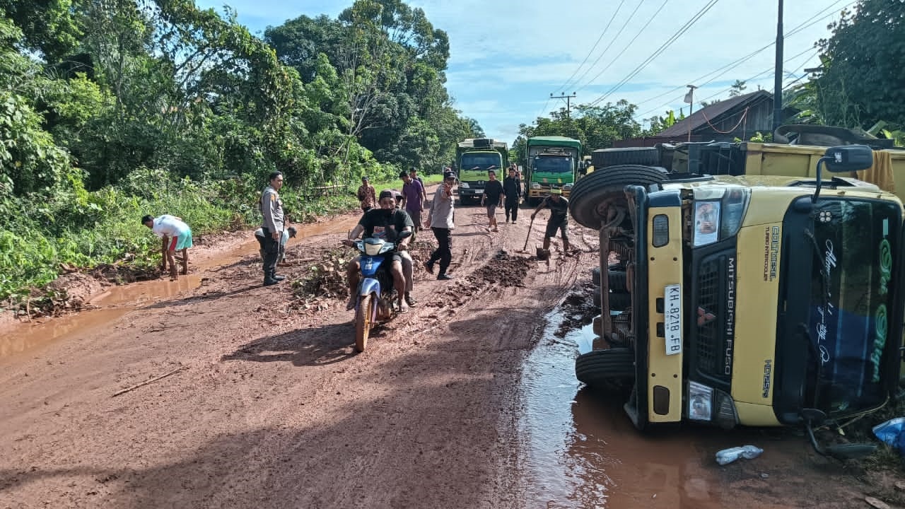 TERJEBAK: Sebuah truk yang terbalik di titik jalan yang rusak parah, membuat ratusan kendaraan lainnya harus antre melintas di Jalan Tjilik Riwut km 35 Desa Cempaka Mulia, Kamis (15/5).