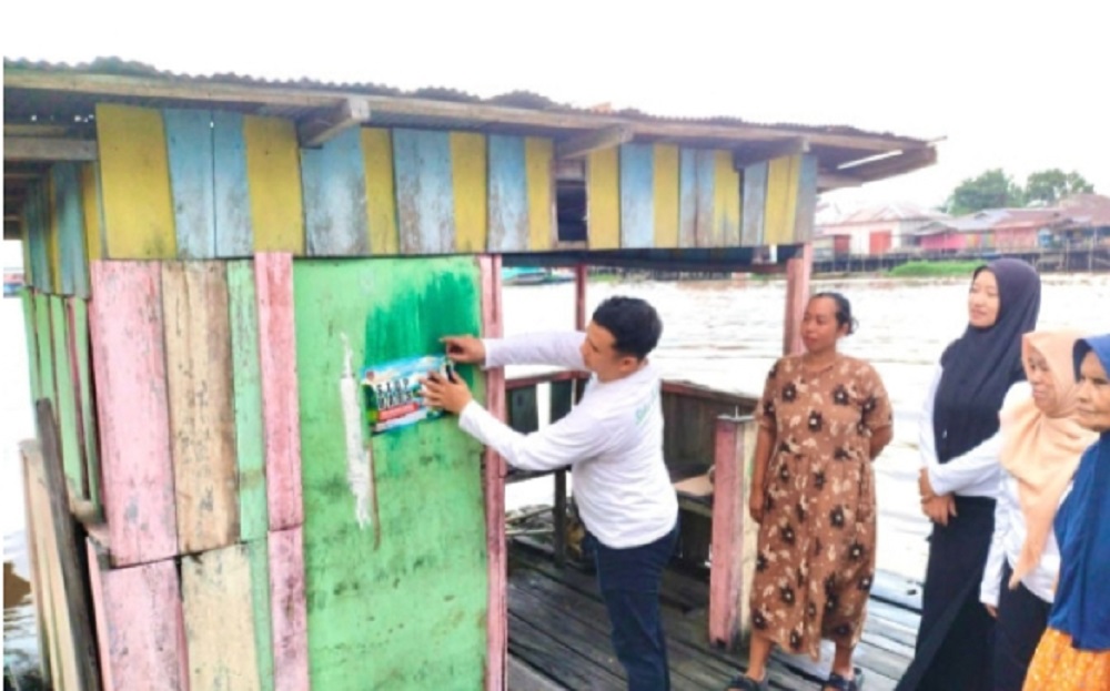 Lurah Raja Seberang dan masyarakat memasang stiker stop buang air besar sembarangan di salah satu jamban di pinggiran Sungai Arut, Senin (16/6).