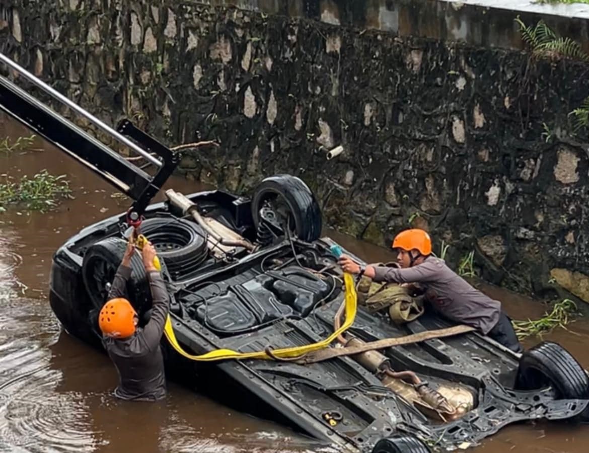 Personel Pammat Subdit Gasum Ditsamapta Polda Kalteng saat mengevakuasi 1 unit mobil yang terbalik di dalam parit di Jalan Ir Soekarno, Palangka Raya, Jumat (20/6) pagi.